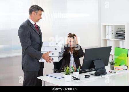 Mature businessman donnant pile de dossiers à assistante in office Banque D'Images