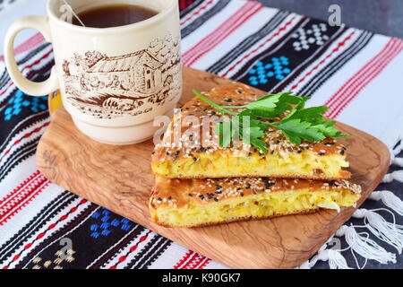 Deux morceaux de tarte à la carotte chou blanc sur une plaque noire avec une tasse de thé et le reste de la tarte sur un fond textile. petit-déjeuner sain. simpl Banque D'Images