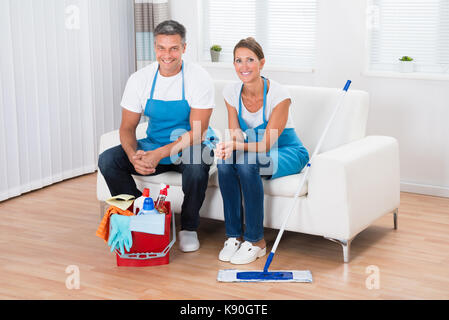 Deux heureux cleaners sitting on couch in living room Banque D'Images