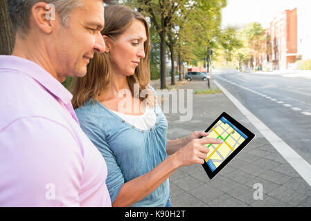 Happy couple looking at digital tablet sur la carte gps Banque D'Images