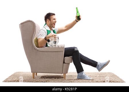 Heureux fan de foot avec un foulard et une bouteille de bière assis dans un fauteuil isolé sur fond blanc Banque D'Images