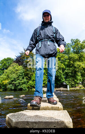 L'homme de traverser la rivière à l'aide de l'usure des tremplins à Stanhope, comté de Durham. Banque D'Images