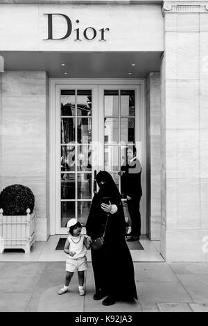 Une femme musulmane portant la burqa en tenant un extérieur de la Selfies Dior Fashion Store à New Bond Street, London, UK Banque D'Images