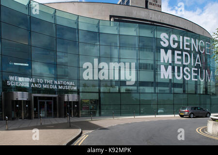 Vue extérieure du Musée des sciences et des médias (Bradford, West Yorkshire, England, UK) - nom affiché sur l'impressionnante façade vitrée incurvée, par des portes. Banque D'Images