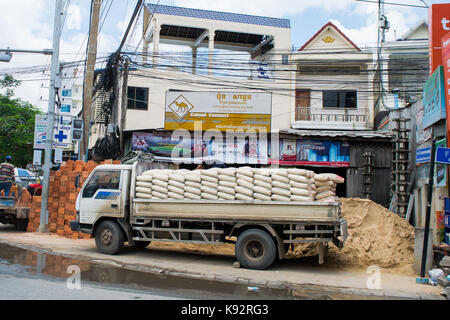 Un camion, bien chargé avec des sacs de ciment et garé sur un trottoir à côté d'un chantier à Phnom Penh, Cambodge, Asie du Sud-Est, l'Indochine. Banque D'Images