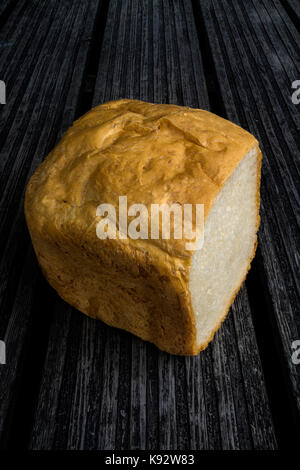 Au four et couper la main miche de pain sur un banc en bois Banque D'Images