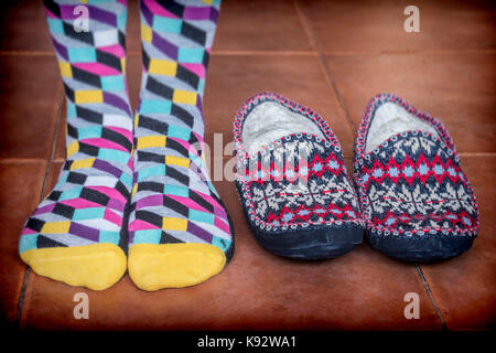 Femme debout avec des chaussettes de couleur à côté d'un hiver chaussons Banque D'Images