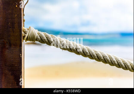 Clôture en bois corde sur pied, de la plage et de la mer en arrière-plan. une clôture en bois avec incrustations de corde sur une plage de sable fin sur l'océan atlantique dans le nord de l'Espagne. Banque D'Images