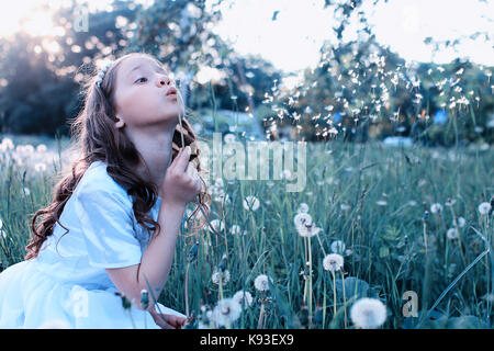 Teen girl blowing seeds à partir d'une fleur de pissenlit spring park Banque D'Images