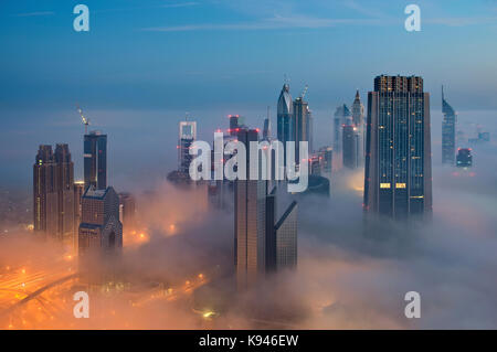 Vue urbaine avec des gratte-ciel lumineux au-dessus des nuages à Dubaï, Émirats arabes unis. Banque D'Images