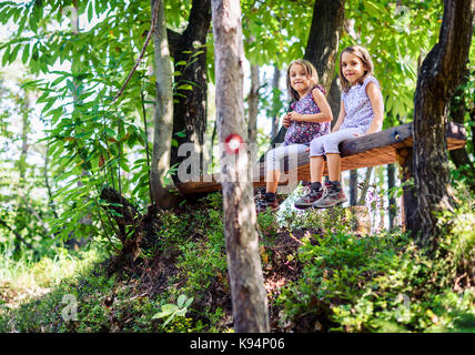 Des jumelles et de repos assis sur un banc en bois. Les enfants actifs sont la randonnée dans les montagnes ou la forêt et se reposent sur un banc en bois dans la nature. Banque D'Images