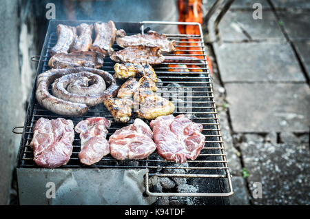 Variété mixte de viande sur le gril du barbecue au charbon. cevapcici, saucisses, ailes de poulet et des hot-dogs sur le barbecue au charbon de barbecue. Banque D'Images