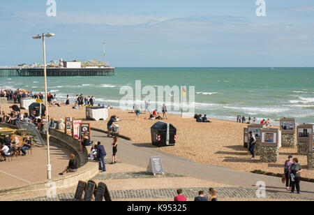 Les gens boire et manger dans un café / restaurant en front de mer et sur la plage de Brighton, East Sussex, Angleterre avec pier en arrière-plan Banque D'Images