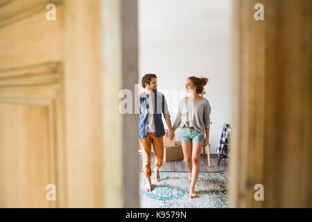 Deux jeunes mariés déménagement dans une nouvelle maison, vous entrez par la porte. Banque D'Images