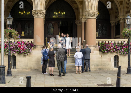 Un couple et leurs invités sur les marches de Northampton Guildhall après le mariage au bureau de l'enregistrement. Banque D'Images