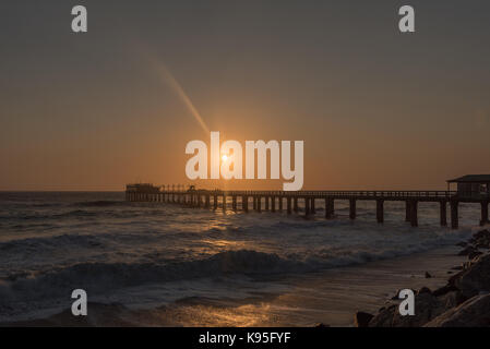 Silhouette de la jetée historique et les pêcheurs contre le soleil couchant, dans le désert du namib en swakopmund sur la côte atlantique de la namibie Banque D'Images