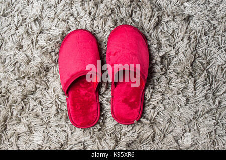 Maison Rouge chaussons sur tapis gris moelleux Banque D'Images