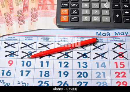 Le calcul sur la calculatrice et stylo d'enregistrement du coût des dons pour la maison de vacances le 9 mai la vie encore d'affaires. Banque D'Images