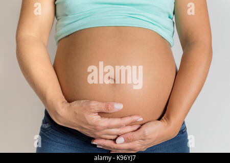 La grossesse. Femme enceinte caressant et en montrant son ventre. Banque D'Images