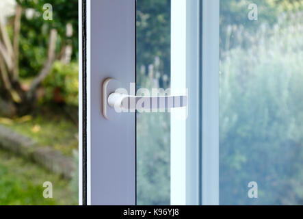 Ouvrez la porte d'une maison familiale. Close-up de la serrure de porte coulissante avec la cour d'arrière-plan. Porte en PVC blanc et double vitrage. Banque D'Images