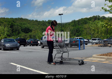 Femme mature regarde dans son sac pour sa liste d'achat. elle a son sac à main dans une poussette et ses clefs dans une main. Banque D'Images