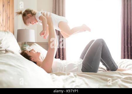 Young happy mother with baby on bed Banque D'Images