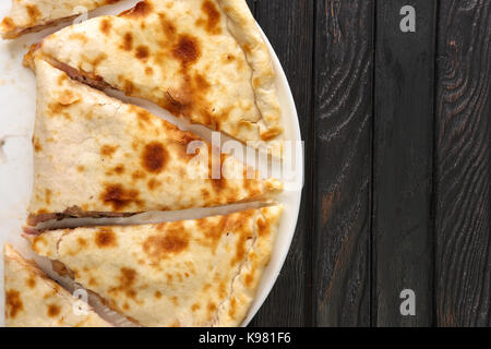 Vue de dessus de la pizza calzone fermée savoureux sur fond de bois foncé Banque D'Images