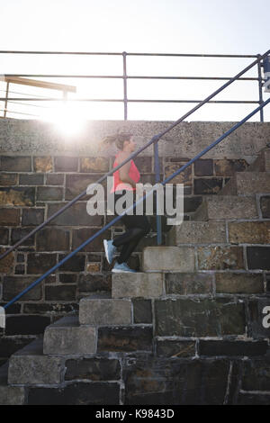 Low angle view of young woman exercising sur mesures au cours de journée ensoleillée Banque D'Images