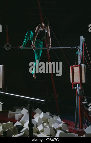 La pratique de la gymnastique gymnaste masculin sur la barre horizontale dans la salle de sport Banque D'Images