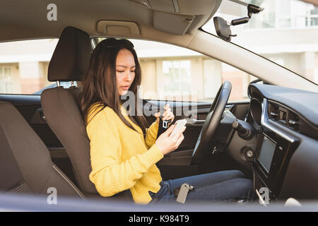 Woman using mobile phone tout en portant la ceinture de sécurité sur un véhicule Banque D'Images