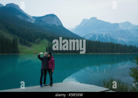 En couple avec selfies mobile phone on pier Banque D'Images