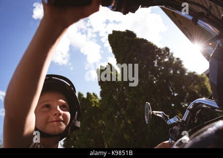 Cute boy assis sur la moto sur une journée ensoleillée Banque D'Images