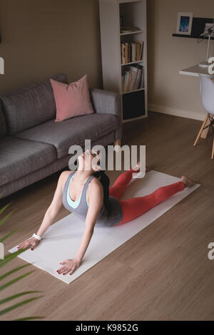 Jeune femme faisant du cobra posent dans l'exercice dans la salle de séjour à la maison Banque D'Images
