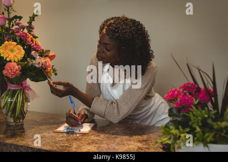 Female florist taking order on mobile phone in flower shop Banque D'Images