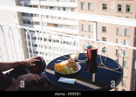 Mid section of man avec petit-déjeuner sur la table assis en terrasse Banque D'Images