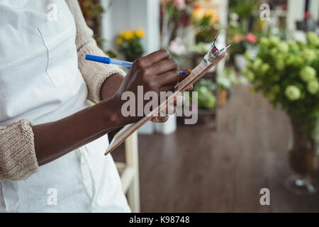 Fleuriste femme écrit et prendre des notes à son magasin de fleur Banque D'Images