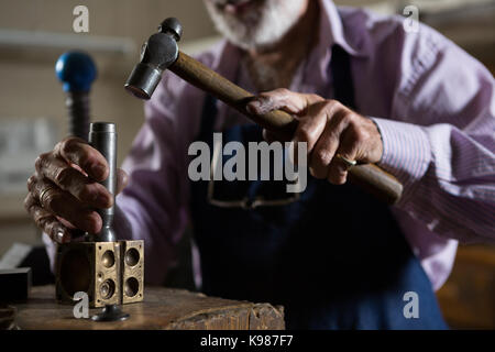 La mi-section de l'aide d'un marteau à l'atelier d'orfèvre Banque D'Images