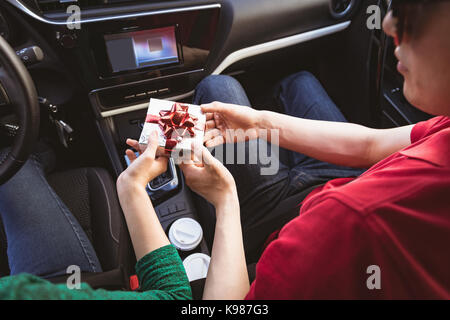 Au milieu du couple giving gift box dans la voiture Banque D'Images
