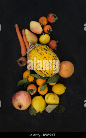 Orange Jaune mixte assortiment de fruits et légumes, ingrédients pour smoothie. melon, Garnett, pamplemousse, carotte, plaqueminier, citron, Coing, poire sur fond noir en ardoise noire Banque D'Images