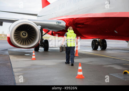 Worker carrying traffic cone et les cales en avion sur la piste Banque D'Images
