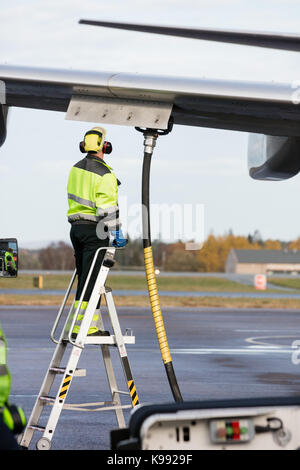 Travailleur homme avion de ravitaillement en se tenant debout sur l'échelle Banque D'Images