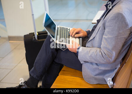 Businessman using laptop in airport terminal Banque D'Images