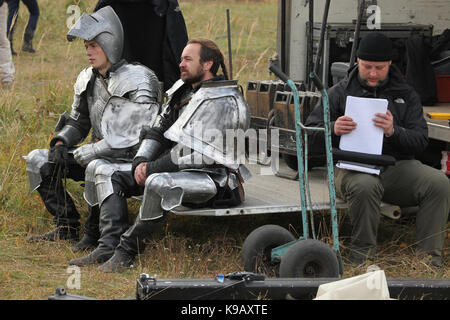 Acteur Tchèque Michal Bednář (L) et un acteur non identifiés habillés comme des chevaliers médiévaux s'asseoir dans les coulisses à côté du membre du personnel pendant le tournage du nouveau cinéma allemand 'Die Ritter' ('Les Chevaliers') réalisé par Carsten Gutschmidt par ordre de ZDF à Milovice en Bohême centrale, en République tchèque, le 23 octobre 2013. Banque D'Images