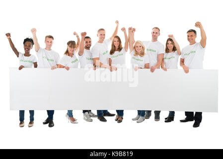 Portrait de bénévoles convaincus avec bras levés holding blank billboard against white background Banque D'Images