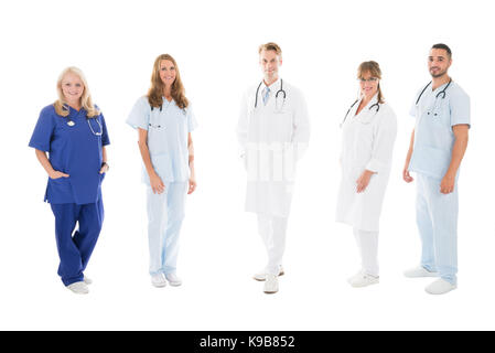 Portrait de l'équipe médicale de confiance dans la rangée debout contre fond blanc Banque D'Images