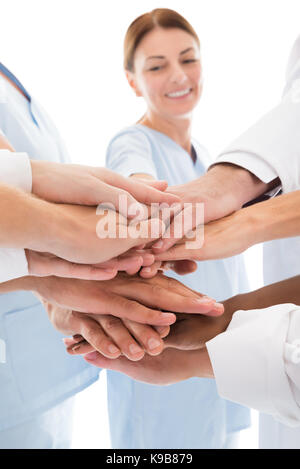 Portrait de l'équipe médicale les mains d'empilage against white background Banque D'Images