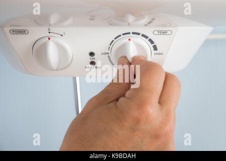 Close-up of a person's hand réglage de température de chauffe eau électrique Banque D'Images