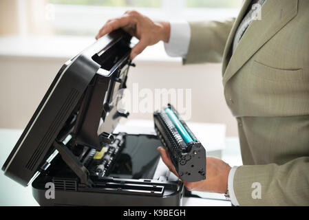 Close-up of businessman fixant en cartouche photocopieur in office Banque D'Images