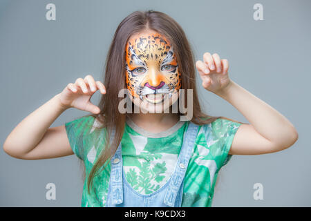 Belle fille avec un tigre peint sur son visage sur un fond gris Banque D'Images