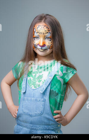 Belle fille avec un tigre peint sur son visage sur un fond gris Banque D'Images